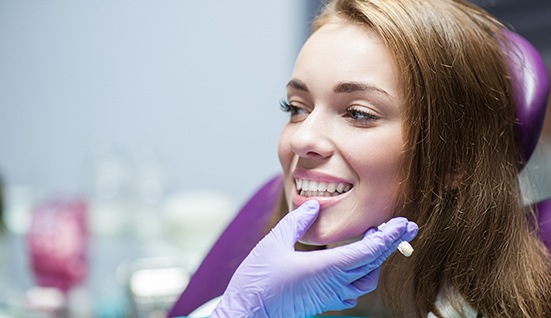 Dentist’s gloved hand touching patient’s jaw to see results
