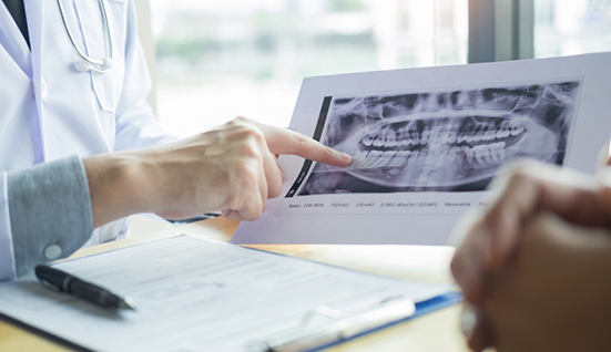 Dentist gesturing to an x ray of teeth