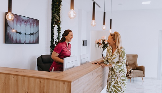 Dental receptionist and patient smiling at each other