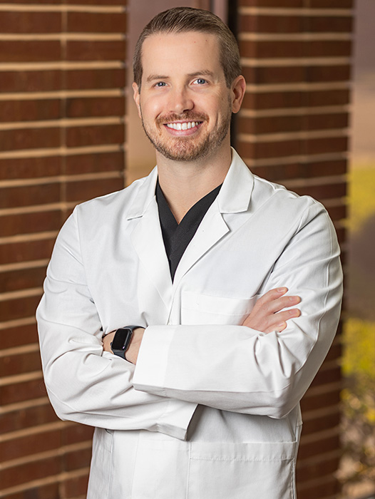 Orlando dentist Doctor Kyle Schnackenberg smiling in a white lab coat