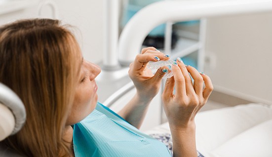 Patient holding clear aligner in treatment chair