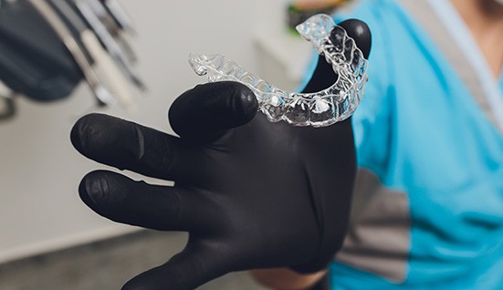 Dentist with black gloves holding Invisalign aligner
