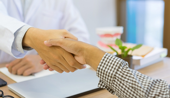 Two people shaking hands across a table