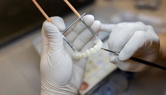 Machine in a dental lab creating a denture based on an impression of a patients teeth on a nearby screen